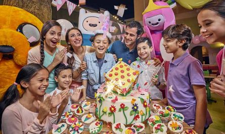 Birthday party celebration at IMG Worlds of Adventure with kids, parents, a themed cake, and cartoon character
